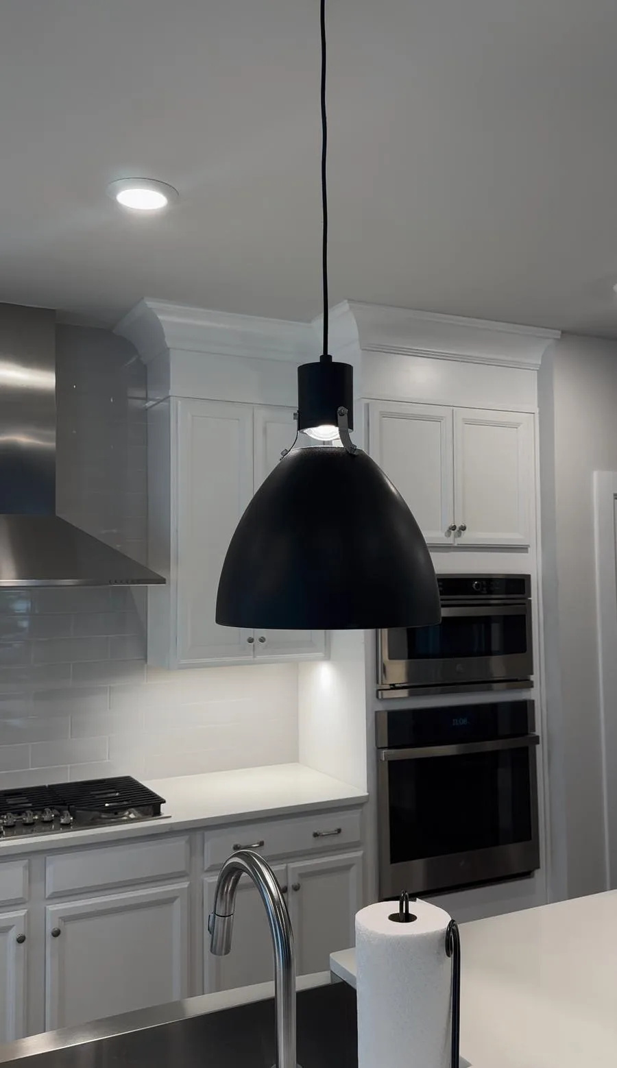 Wide view of completed West Chester kitchen — island, sink, range hood, oven tower, and pendant lamp visible